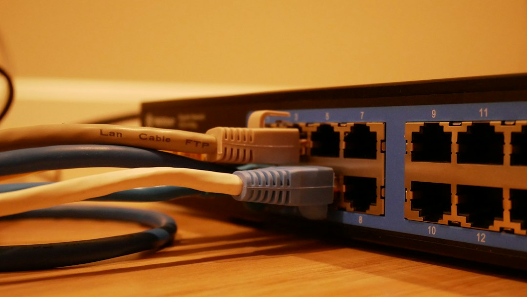 Cabos de rede conectados a um switch numerado sobre uma mesa de madeira.